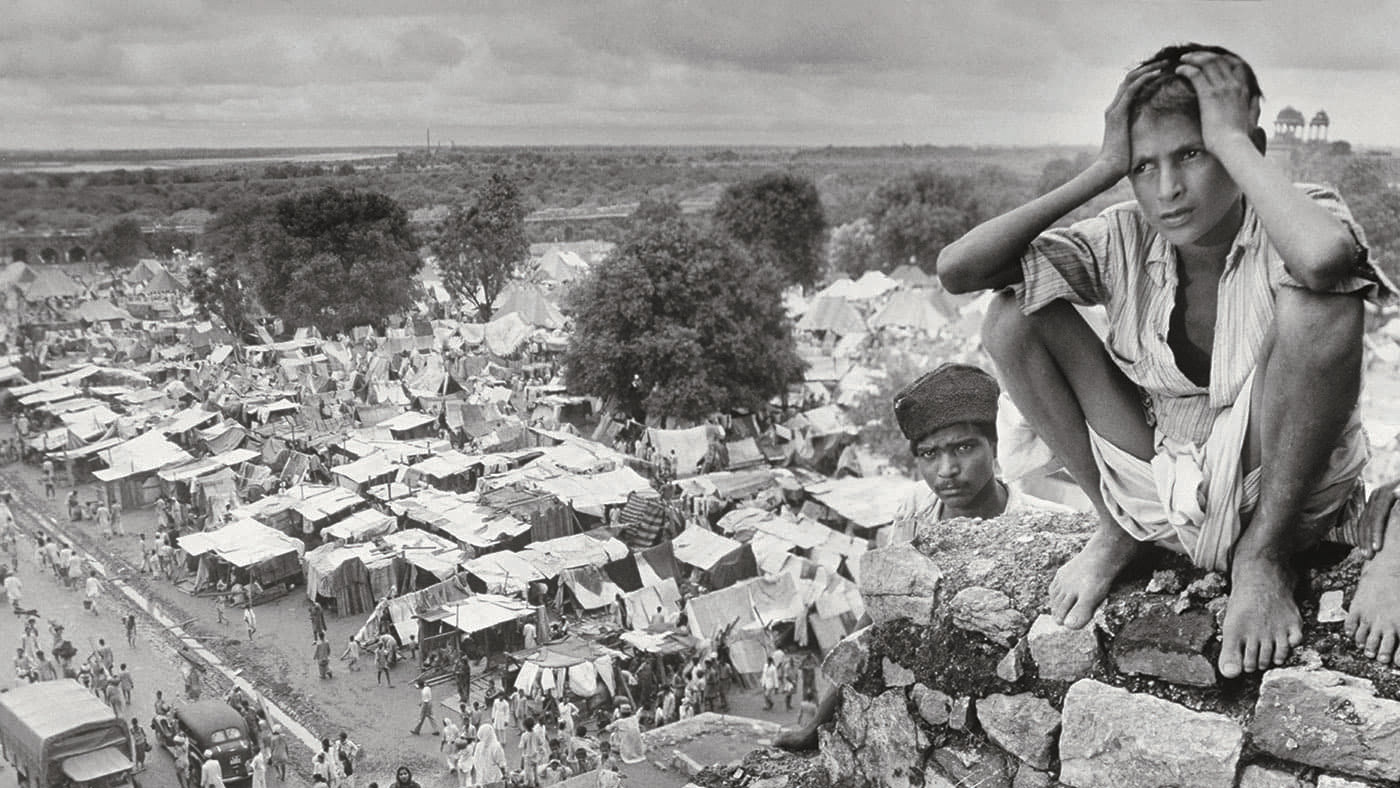 A young refugee in Delhi in August 1947 squats on the rubble of a ruined Sultanate monument
